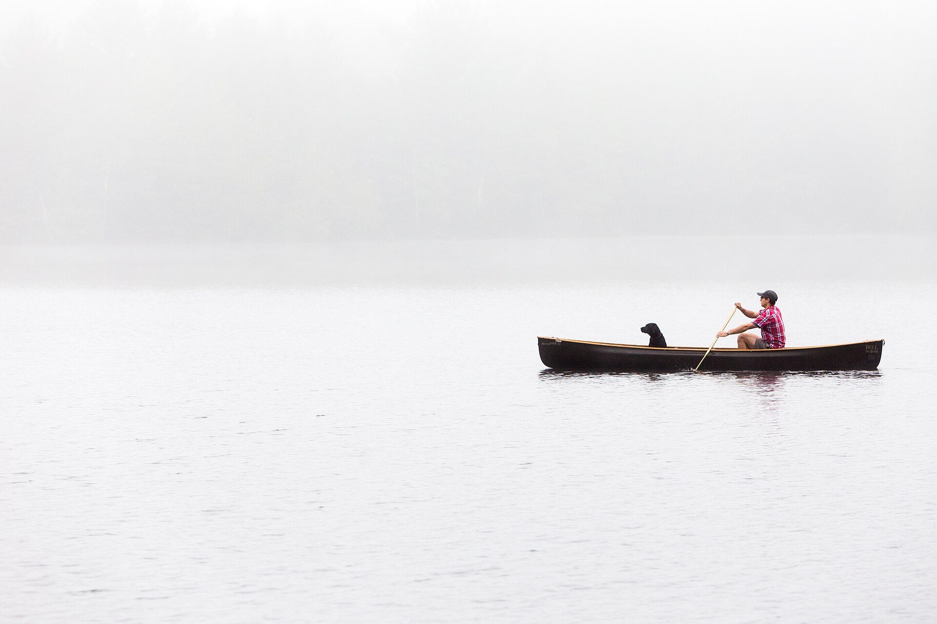 A canoe on a still lake in morning fog